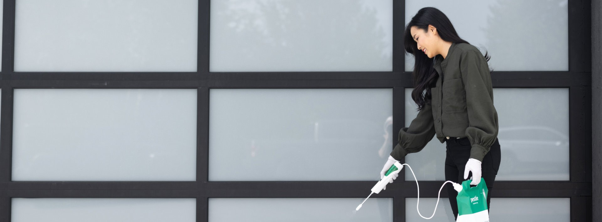Woman spraying Pestie infront of garage door