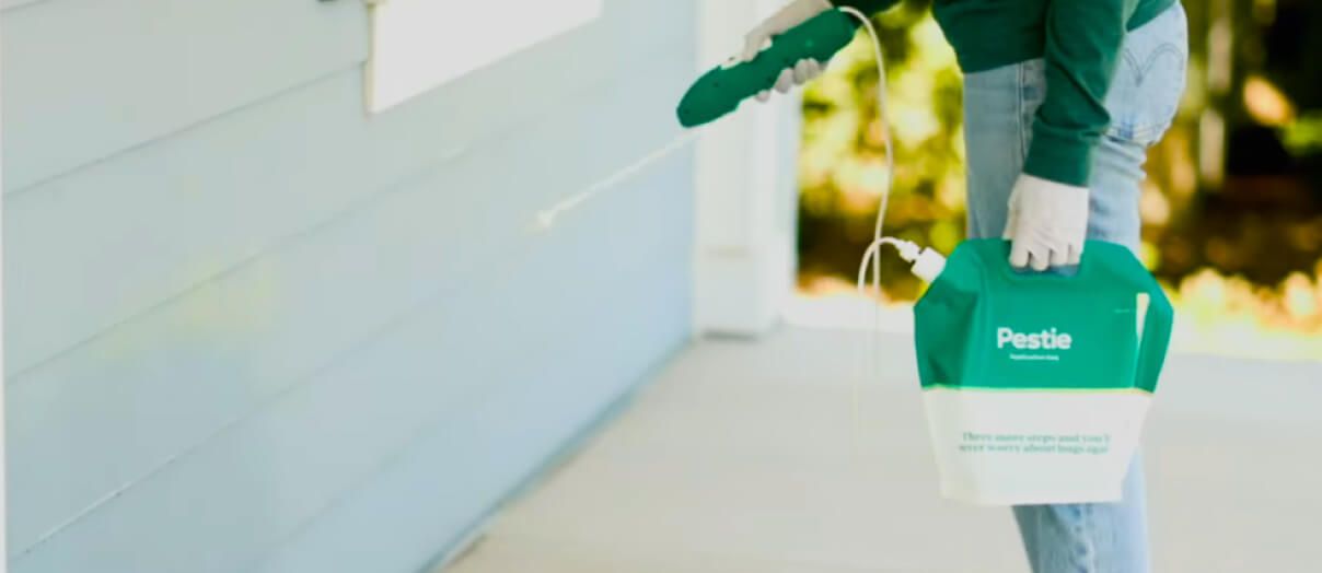 Woman spraying Pestie on blue house